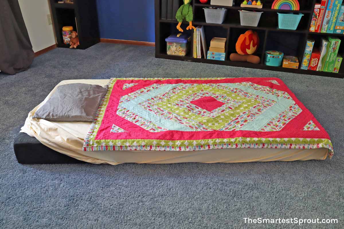 Nugget couch floor bed setup with blanket and pillow for quiet rest time
